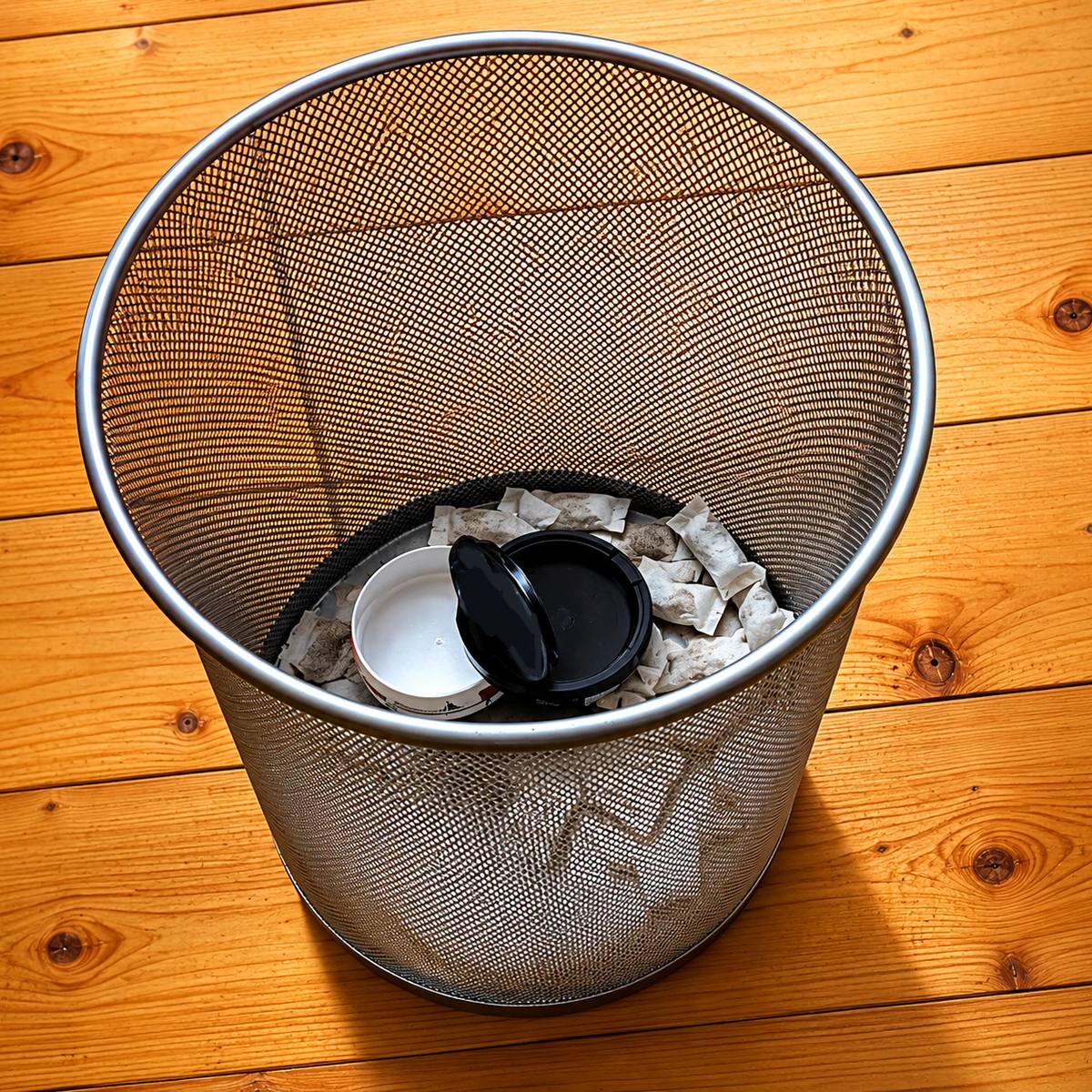 Snus-Dose und Beutel im Mülleimer